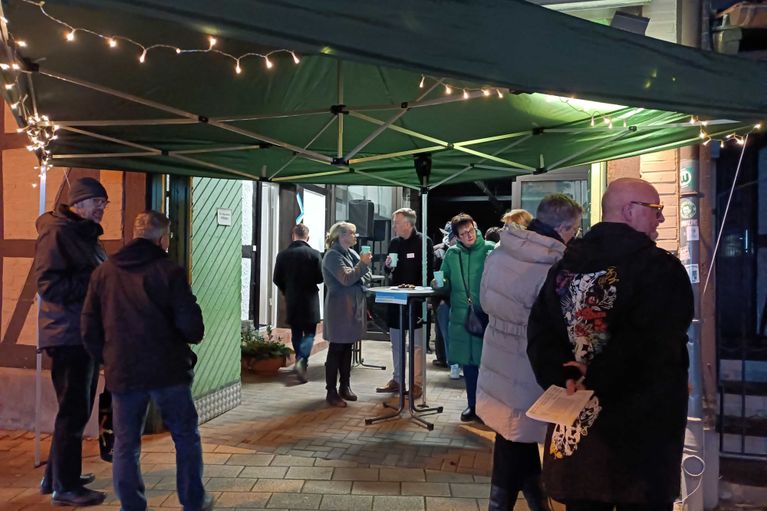 Der Eingang zum Zentrenbüro Vorsfelde, dekoriert mit Pavillon und Lichterketten. Menschen unterhalten sich und trinken Glühwein und Punsch.